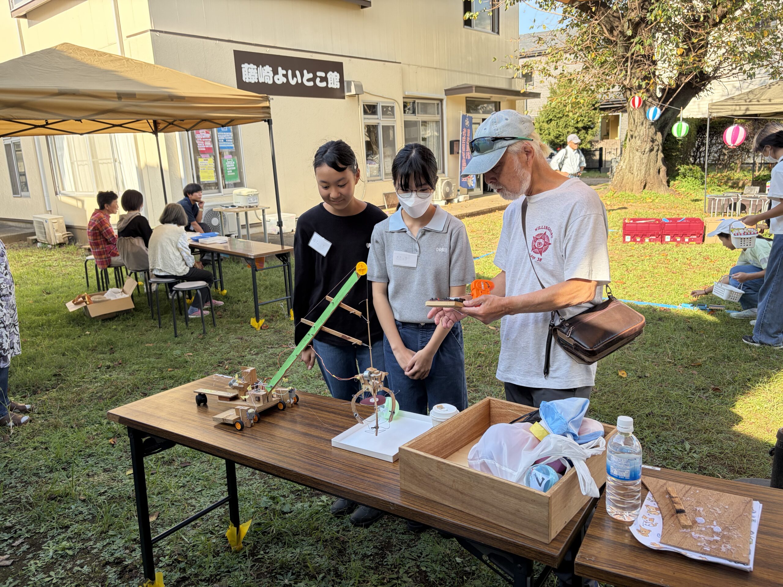 藤崎よいとこ館の前で、手作りクレーンゲームを担当する中学生と地域の方